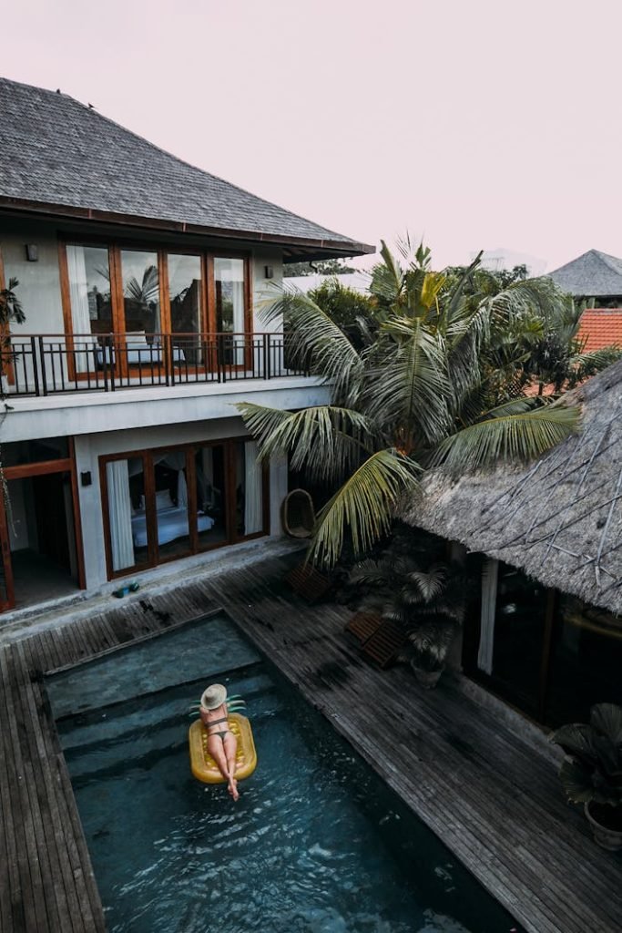 Woman relaxing on a float in a tropical resort pool surrounded by lush greenery.